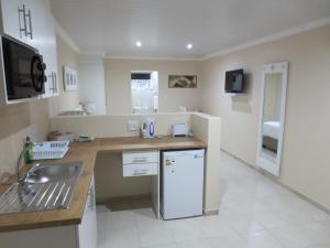 a kitchen with a sink and a white refrigerator at Masada Guest House in Langebaan