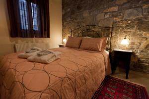 um quarto com uma cama grande e uma parede de pedra em Althaia em Áno Khóra