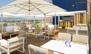 ein Restaurant mit weißen Tischen, Stühlen und Sonnenschirmen in der Unterkunft Salles Ciutat del Prat Barcelona Airport in El Prat de Llobregat