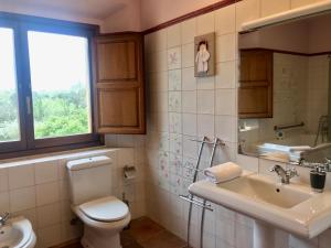 ein Badezimmer mit Toilette und Waschbecken und einem Fenster in der Unterkunft Mas Duc in Brunyola