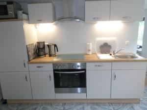 a kitchen with white cabinets and a stove and a sink at Ferienwohnung DAHEIMchen in Glücksburg