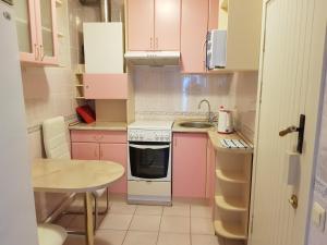 uma pequena cozinha com armários cor-de-rosa e um lavatório em Naiza Guesthouse and Apartments em Jūrmala
