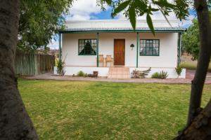 a white house with a door and a yard at Olive Grove Guest Farm in Beaufort West