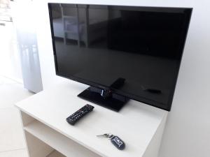 a television on a white table with two remote controls at Residence Kullat in Velipojë