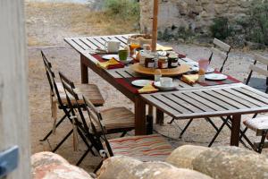 a wooden table with chairs and food on it at Mas de la Gonnette in Venasque +15 photos