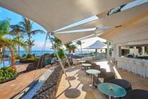 an outdoor patio with tables and chairs and the ocean at Hipotels Natura Palace Adults Only in Playa Blanca