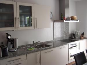 eine Küche mit weißen Schränken und einer Spüle in der Unterkunft Refugium Prerow in Prerow + 7 Fotos