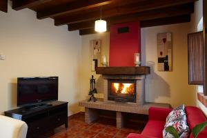 a living room with a fireplace and a tv at La Piñera in Siero