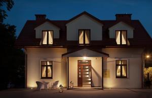 a house lit up at night with chairs in front at Apartamenty Willa w Dolinie in Tarnów