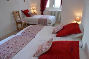 duas camas num quarto com vermelho e branco em L'Ecureuil em Gérardmer