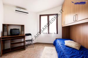 a bedroom with a bed and a desk and a tv at Case Vacanza Baia Chia Aiosardegna in Chia