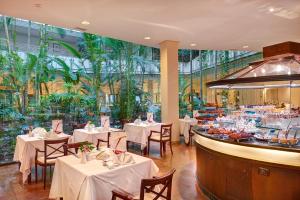 a restaurant with white tables and chairs and plants at Hipotels Natura Palace Adults Only in Playa Blanca
