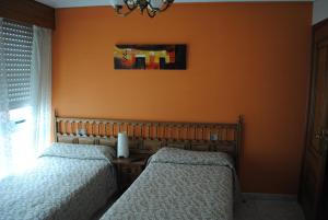 2 camas en un dormitorio con pared de color naranja en Choyo 2, en Ferrol