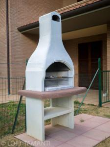 un horno de pizza sentado fuera de un edificio en Loft Tamanti, en Borgo Santa Maria