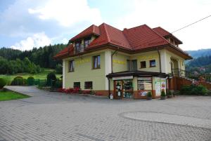 um edifício com um telhado vermelho numa estrada de tijolos em U Kuby em Korbielów