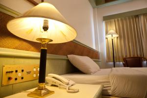 a hotel room with a phone and a lamp on a table at Tanyong Hotel in Narathiwat