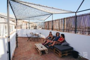 trzy kobiety siedzące na kanapie na patio w obiekcie Black Swan Hostel Sevilla w Sewilli