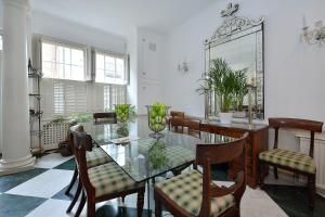 a dining room with a glass table and chairs at Ennismore Mews in London