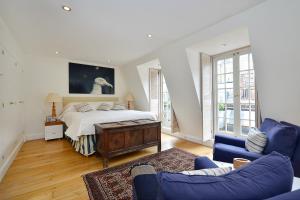 a bedroom with a bed and a blue couch at Ennismore Mews in London