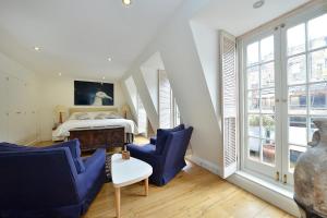 1 dormitorio con 1 cama y 2 sillas azules en Ennismore Mews, en Londres