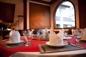 stół z czerwoną tkaniną stołową z serwetkami i kieliszkami do wina w obiekcie Tanyong Hotel w Narathiwat