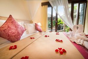 sypialnia z łóżkiem z czerwonymi kwiatami w obiekcie Pecatu Ubud Guest House w mieście Ubud