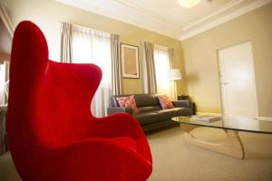 sala de estar con silla roja y sofá en Globe Apartments, en Wagga Wagga