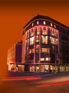 un edificio con luces rojas en el lateral. en Hotel Palas en Kazanlŭk