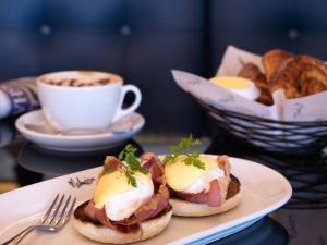 a plate with two breakfast sandwiches and a cup of coffee at Malmaison London in London
