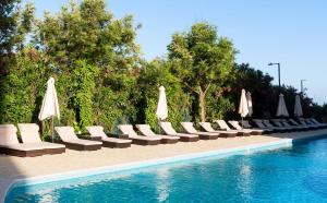a row of chairs and umbrellas next to a swimming pool at TRYP by Wyndham Lisboa Caparica Mar in Costa da Caparica