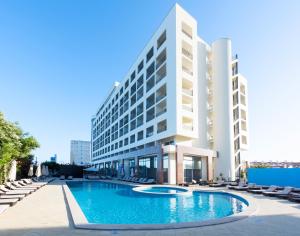 a hotel with a swimming pool in front of a building at TRYP by Wyndham Lisboa Caparica Mar in Costa da Caparica