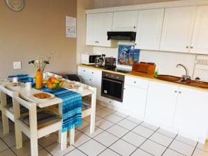 a kitchen with white cabinets and a table with food on it at Dumela Margate Flat No 3 in Margate