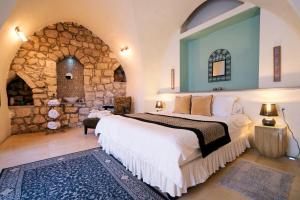 a bedroom with a large bed and a stone wall at Artists' Colony Inn Zefat in Safed