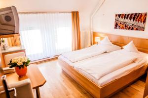 ein Schlafzimmer mit einem Bett, einem Tisch und einem Fernseher in der Unterkunft Hotel Martinihof in Münster