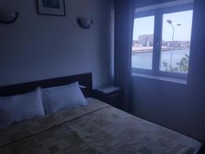 a bedroom with a bed with a large window at Hotel El Layeli in Sfax