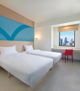 two beds in a hotel room with a window at Hop Inn Hotel Makati Avenue Manila in Manila