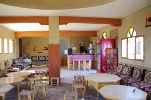 a living room with tables and chairs and a kitchen at Tifina Caravanserail d'Arfoud in Erfoud