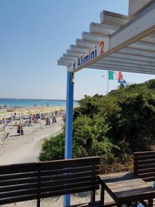 um banco sentado ao lado de uma praia com uma placa em Serra Degli Alimini 2 em Alimini