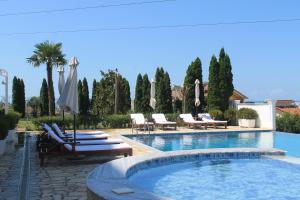 een zwembad met ligstoelen en parasols bij Hotel Aleksandrus Jardin in Durrës