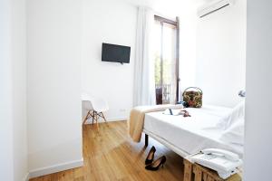 a white bedroom with a bed and a window at Som Nit Born in Barcelona