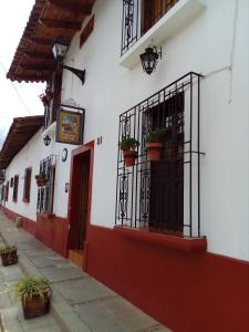 a white and red building with potted plants on it at Las Margaritas Hotel Posada in Tapalpa