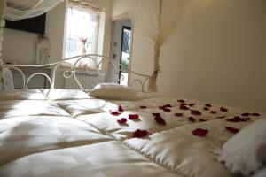a white bed with red rose petals on it at La Dolce Casetta in Grottaferrata