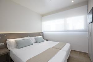 a bedroom with a large white bed with two pillows at Don Cesar Boutique Apartments in Benidorm