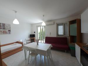 sala de estar con mesa blanca y sofá rojo en Sicily for Rent, en Mascali