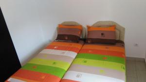 a bed with colorful pillows on top of it at Aparmani Family 1 in Sutomore