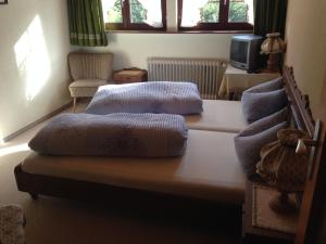 a room with two beds and a tv and windows at Café - Pension Bernreutehof in Vöhrenbach