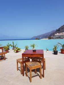 a wooden table and chairs on a patio with water at Casa D'Mar in Ponta do Sol