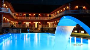 a swimming pool in front of a house at night at Artemis Resort Wellness Hotel in Štúrovo