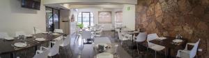 um restaurante com mesas e cadeiras brancas e uma parede de pedra em Hotel La Riviera em Culiacán