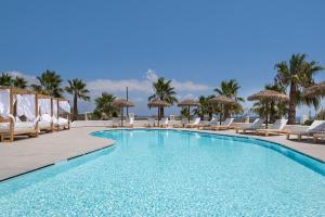 a beach with a pool, chairs, and a pool table at Casa Vitae Suites in Kamari